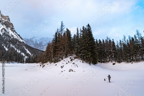 Woman with dog on a walk in winter scenery in Austria.