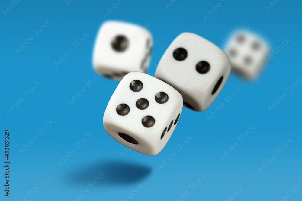White playing dice cubes in motion on the blue surface, selective focus White playing dice cubes in motion on the blue surface, selective focus