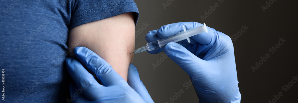 COVID-19 vaccine shot, doctor holds syringe and makes injection to woman patient - obrazy, fototapety, plakaty 