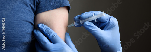 COVID-19 vaccine shot, doctor holds syringe and makes injection to woman patient photo