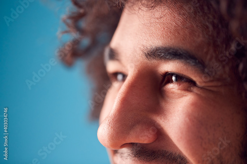 Tableau sur toile Close Up On Eyes Of Smiling Young Man Against Blue Background In Studio