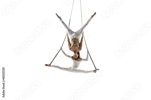 Freedom. Couple of young acrobats, circus athletes isolated on white studio background. Training perfect balanced in flight, rhythmic gymnastics artists practicing with equipment. Grace in performance