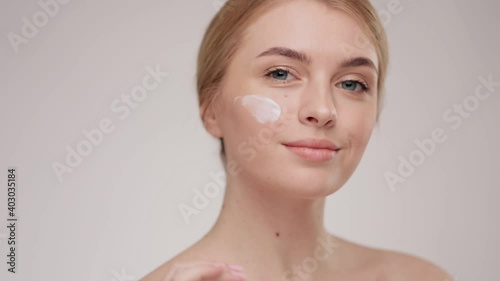 Slow motion portrait young woman uses creams of her face. Concept for fresh moisturized skin beautiful closeup cosmetic face happy healthy model. Young blonde hair woman take care of her skin.