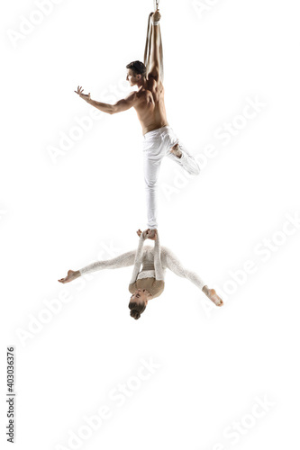 Catching. Couple of acrobats, circus athletes isolated on white studio background. Training perfect balanced in flight, rhythmic gymnastics artists practicing with equipment. Grace in performance.