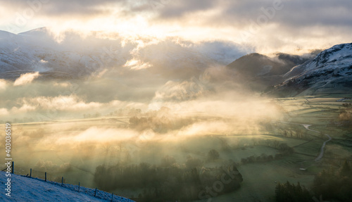 Atmospheric sunlight shining through early morning mist in the Lake District © tranquillian