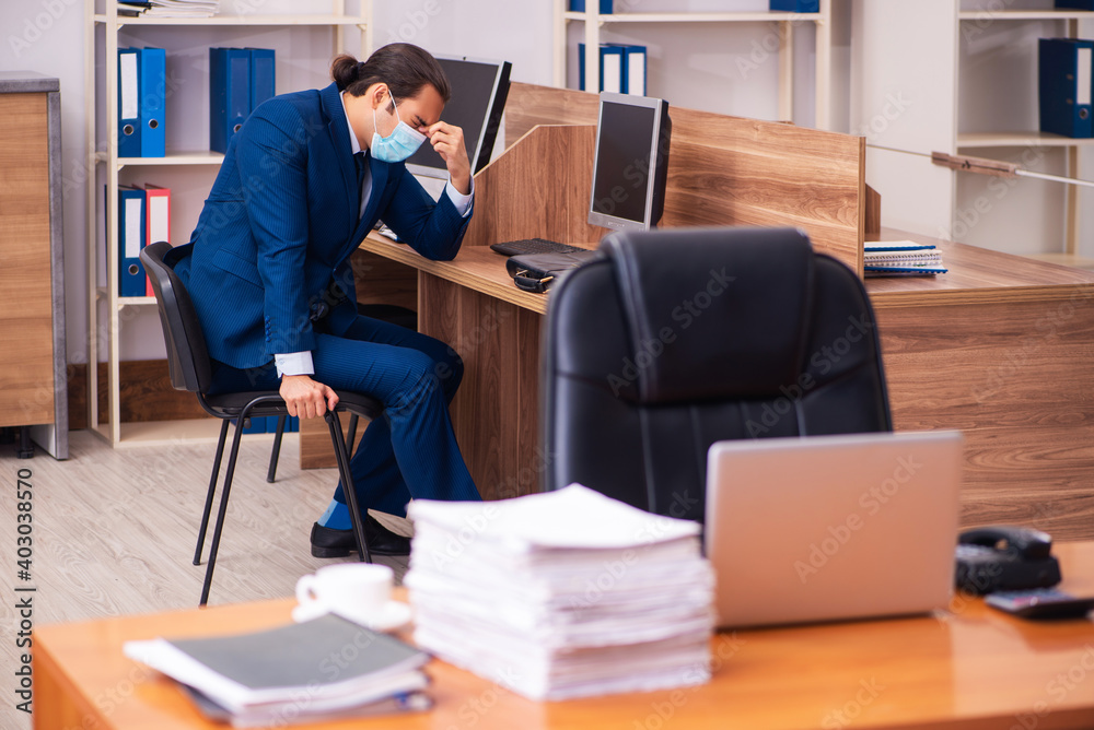 Young male employee working in the office wearing mask Young male employee working in the office wearing mask