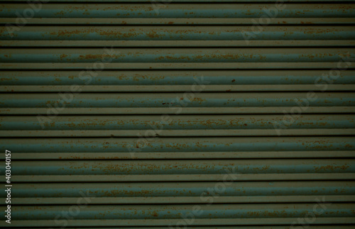 Canvas Print Old green rusting metal security shutters full frame background texture with hor