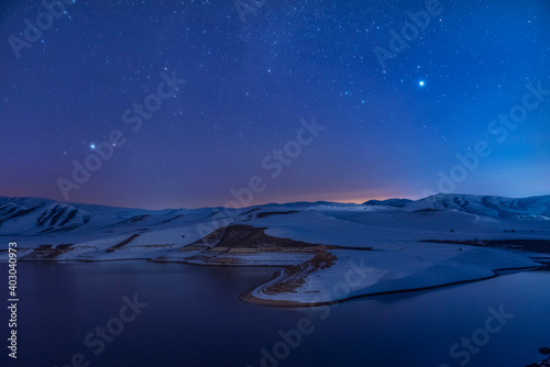  Beautiful winter landscape. Panoramic view on the lake  and mountains peaks snow-covered at the starry night. 