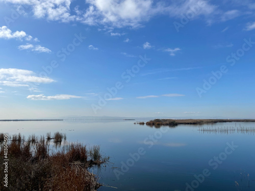 Tranquil lake or estuary at sunrise or sunset with a glow on the horizon and reflection of the blue sky and clouds on the water