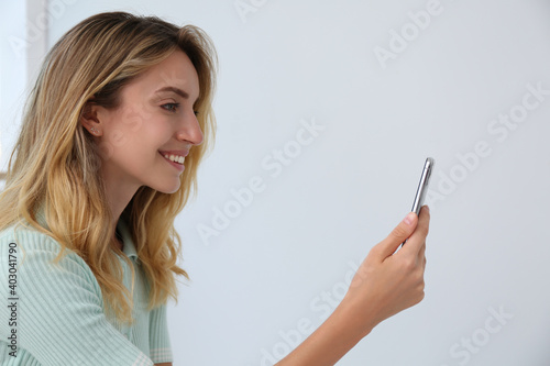 Young woman unlocking smartphone with facial scanner indoors. Biometric verification