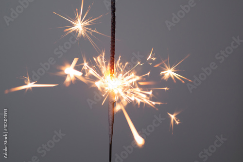 Sparkler lit burning down on a gray background 