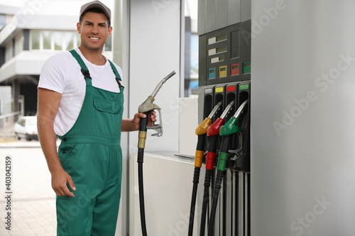 Worker taking fuel pump nozzle at modern gas station