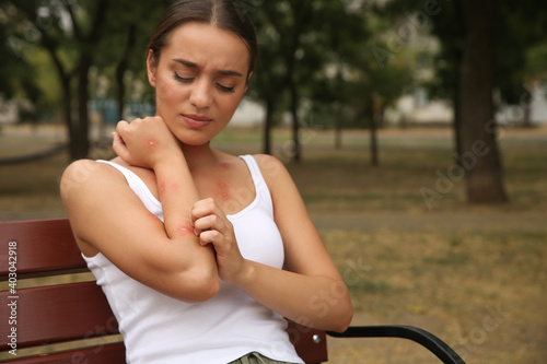 Foto Woman scratching arm with insect bite in park. Space for text
