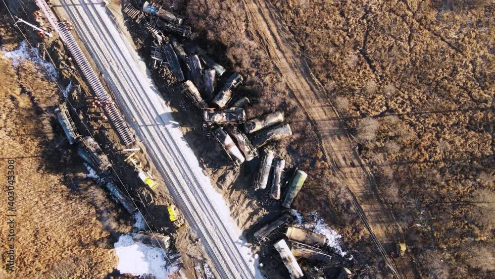 A train wreck on the railway, scattered cisterns, a locomotive is passing. Aerial view of the accident - a crash with damaged wagons lying next to the rails. Rescuers carry out repair work.