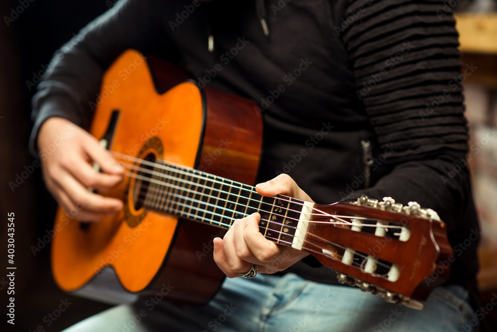 Obraz premium Hands of man playing guitar. Guitarist holding an acoustic guitar. Handsome man playing guitar at the pub.