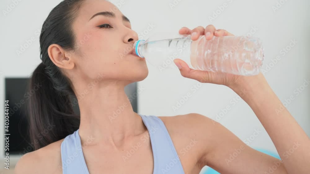 Close up woman drinking water after exercise in her home Close up woman drinking water after exercise in her home