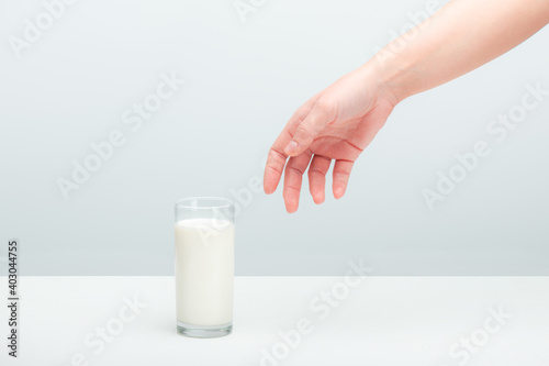 naked hand of a young woman reaching for a glass of milk staying on a table