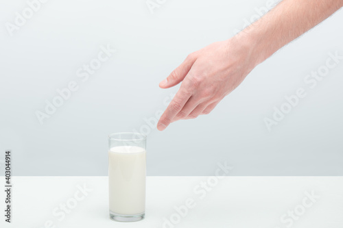 naked hairy hand of a young man reaching for a glass of milk staying on a table