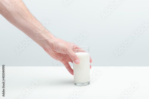 man's hand taking a glass of milk from a table.