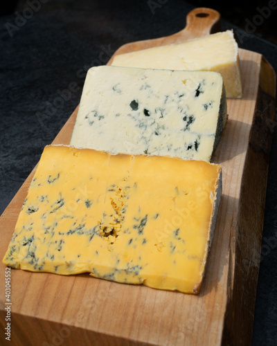 A selection of three cheeses on a wooden platter on an outdoor table in Cartmel, Cumbria photo