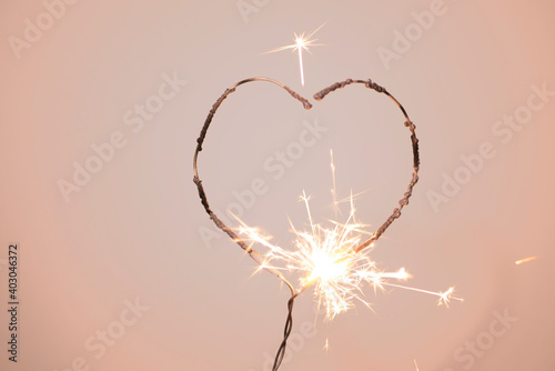Heart shape sparkler
burning on a delicate pink background with love background concept.