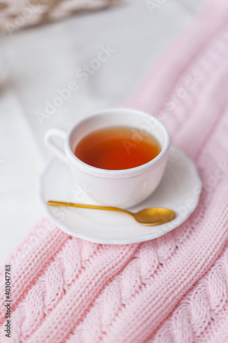 A mug of hot tea, a knitted pink plaid on the bed. Breakfast in bed. Cozy.