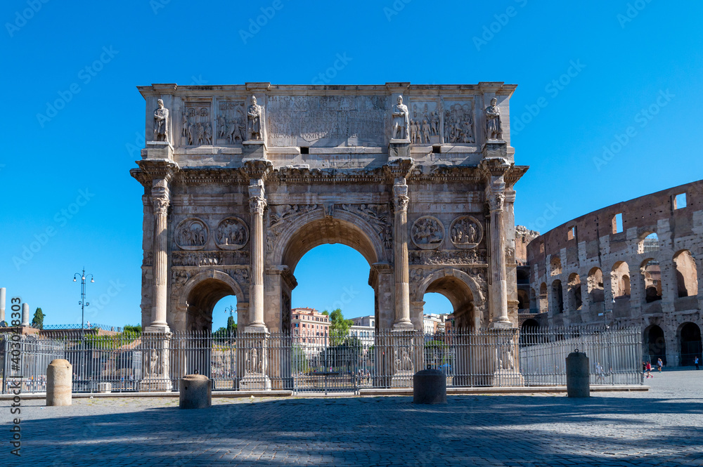 Arch of Constantine near the Colosseum and the Arch of Titus. Photographed in summer with few tourists, blue sky and clouds. Celebrates the victory of Constantine over Maxentius. Rome, Italy.