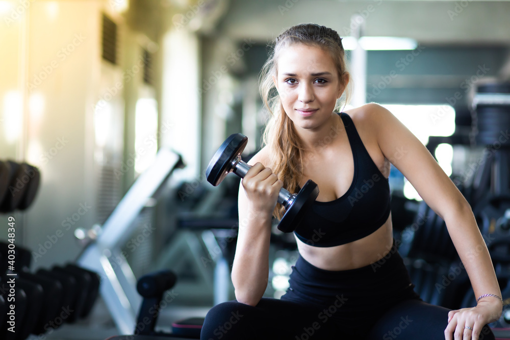 Exercising, Gym, fitness Women concept. athletic young woman doing a fitness workout with dumbbells at indoor gym Exercising, Gym, fitness Women concept. athletic young woman doing a fitness workout with dumbbells at indoor gym