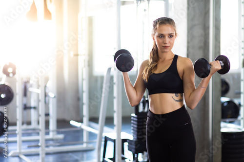 Exercising, Gym, fitness Women concept. athletic young woman doing a fitness workout with dumbbells at indoor gym