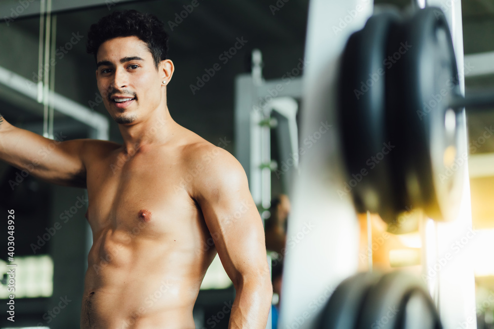 Portait Handsome young man while resting at gym. Man training in a gym Fitness.workout, exercises and healthy concept Portait Handsome young man while resting at gym. Man training in a gym Fitness.workout, exercises and healthy concept