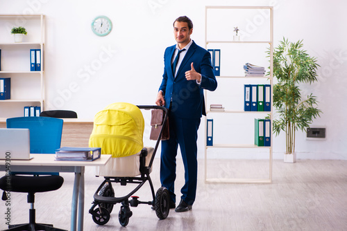 Young male employee looking after kid at workplace
