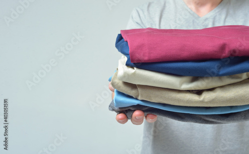 Close-up of a man without a face stretches his arms forward with a stack of clothes