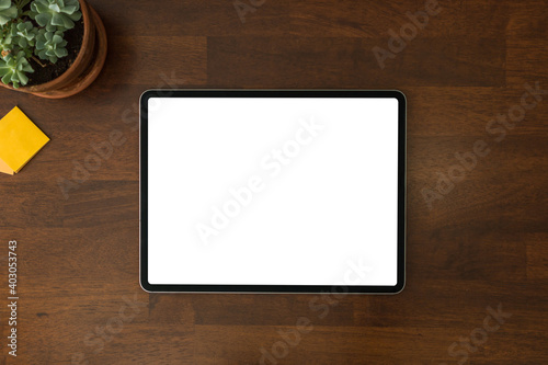 Overhead view of a modern black tablet pc with blank white screen on a home wooden office table and work desk