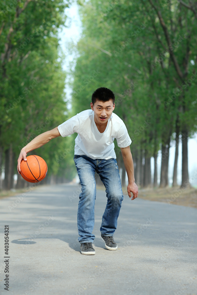 The young man playing basketball in the park 