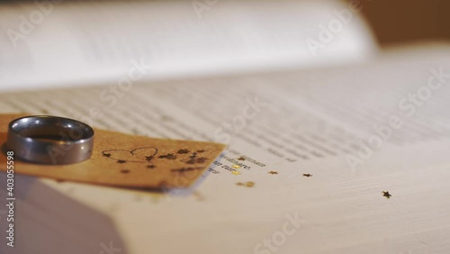 Side reveal of wedding band on a tag with stars, heart placed on a book photo