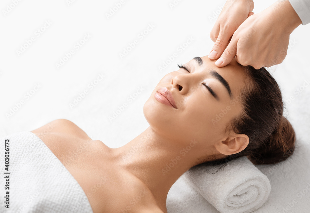 Attractive young korean woman receiving acupressure head massage in spa salon