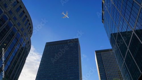 Looking up passing airplane at high altitude above London city skyline  financial distrtict  United Kingdom