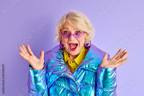 cheerful woman 60 years old in warm winter jacket , smile at camera, shine with happiness, young inside. isolated on purple studio background photo