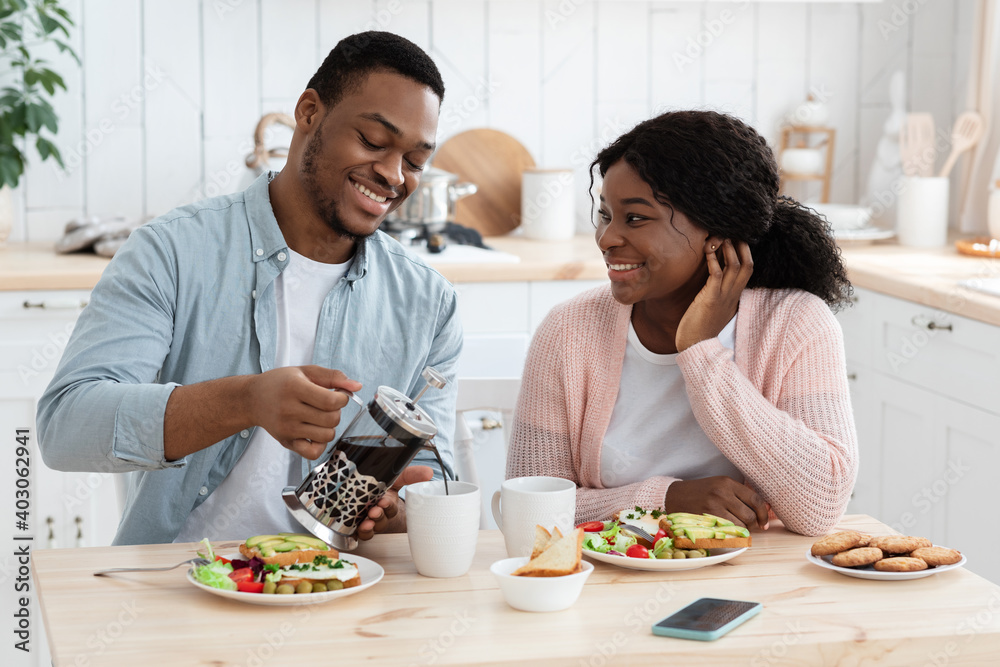Happy African American Couple Eating Breakfast And Drinking Coffee In KItchen Together