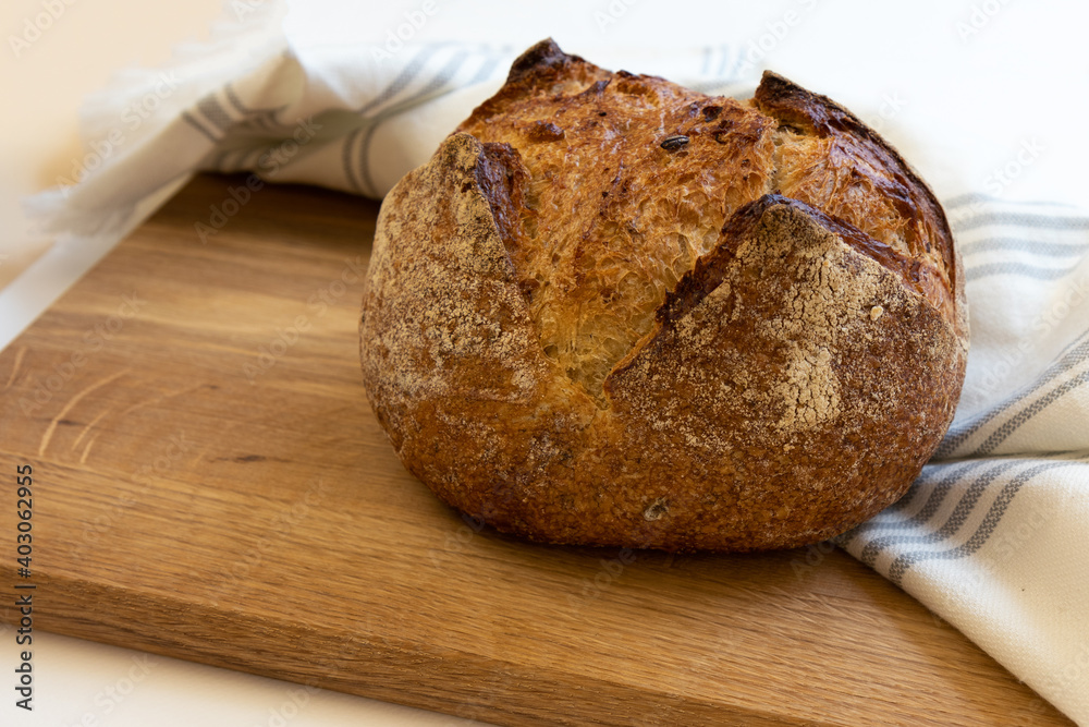 Loaf of bread wrapped in white linen towel lying on a wooden table Loaf of bread wrapped in white linen towel lying on a wooden table