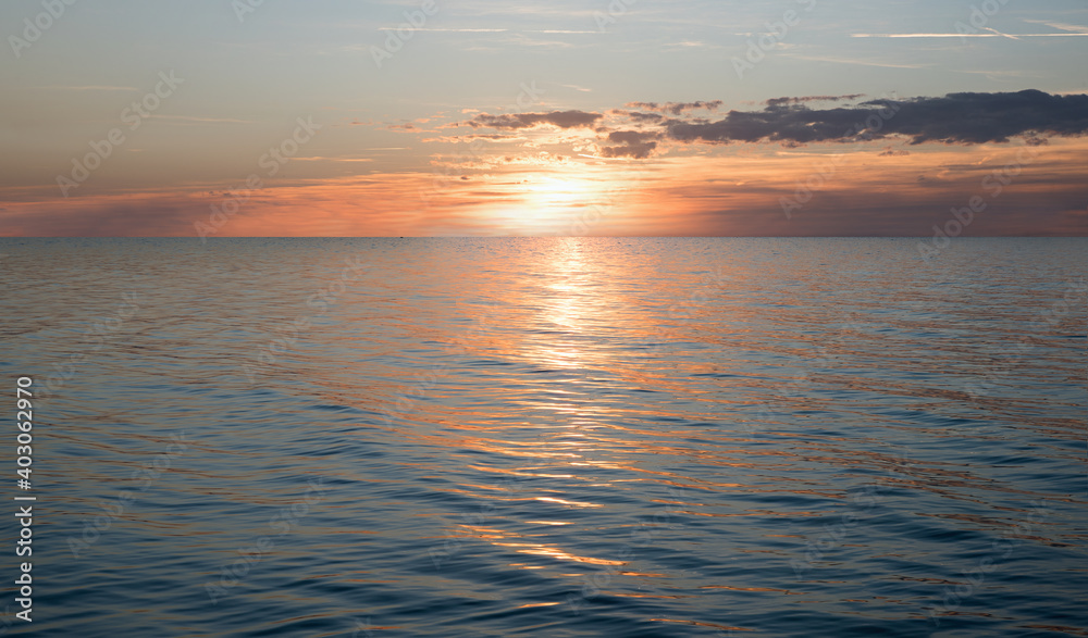 Obraz premium dreamy sunset scenery with sinking sun over the ocean and water reflection