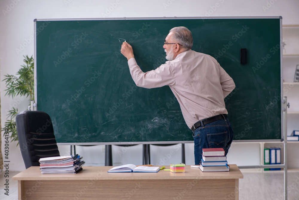 Old male teacher sitting in the classroom Old male teacher sitting in the classroom