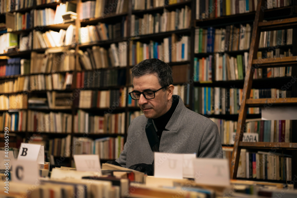 Elegant middle-aged man looking for a book in a classic bookstore
Elegant middle-aged man looking for a book in a classic bookstore
