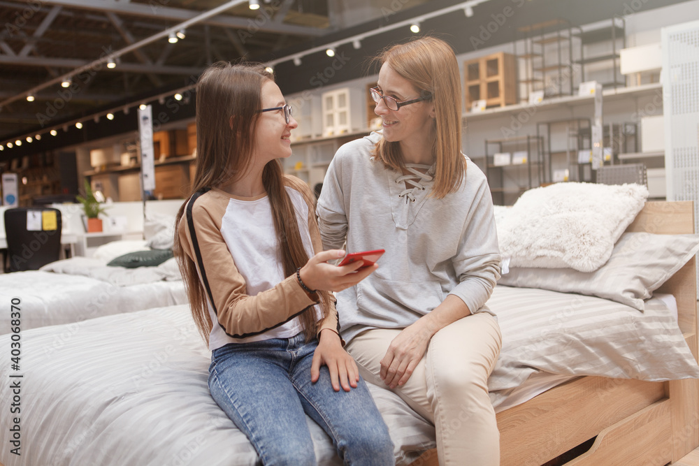 Teenage girl and her mom talking while using smart phone together Teenage girl and her mom talking while using smart phone together