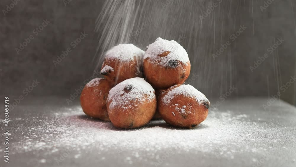 Sugar powder falling on Dutch oil balls delicacy with sugar powder traditionally eaten on New Year's Eve in The Netherlands. Studio low key food still life against a rustic modern kitchen background