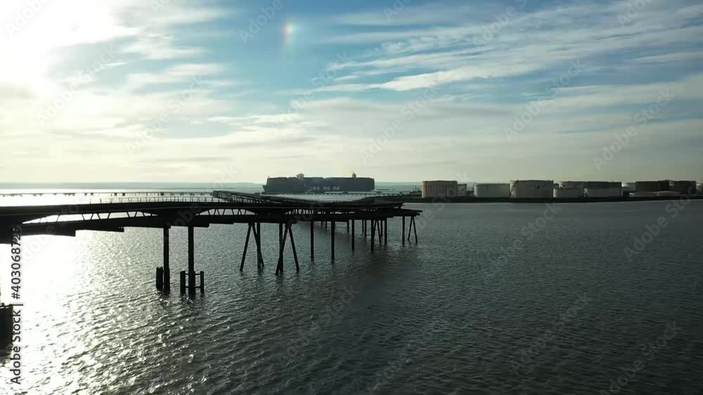 Aerial : HMM huge ship. Drone lifts flying forward towards sun with pier walkway, industrial refinery in view. Mavic 2 Pro HD60fps Aerial : HMM huge ship. Drone lifts flying forward towards sun with pier walkway, industrial refinery in view. Mavic 2 Pro HD60fps