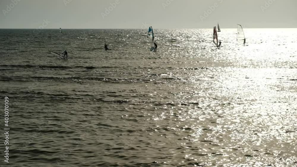 Windsurfers are trying to catch some wind on their boards in a quiet summer afternoon by Tel Aviv coastline, Israel. Windsurfers are trying to catch some wind on their boards in a quiet summer afternoon by Tel Aviv coastline, Israel.