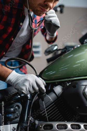 partial view of mechanic making diagnostics of motorcycle engine with stethoscope