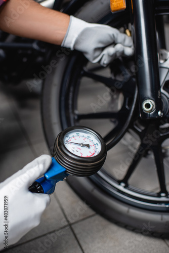 selective focus of manometer in hands of mechanic measuring air pressure in tire of motorcycle