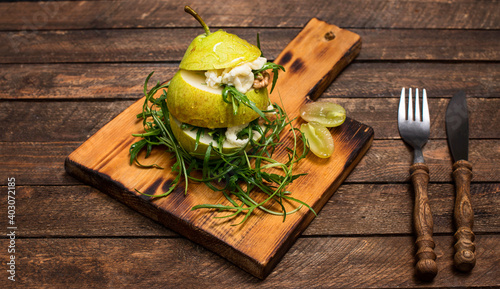 Salad with arugula stracciatella nuts grapes and honey in pear surved on wooden cutting board  on rustic wooden background. photo